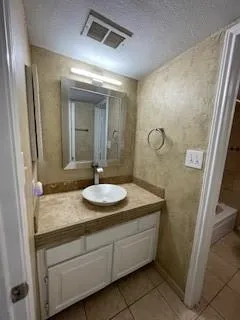 a bathroom with a granite countertop sink a mirror and shower