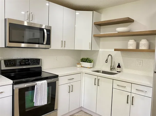 a kitchen with white cabinets and black appliances