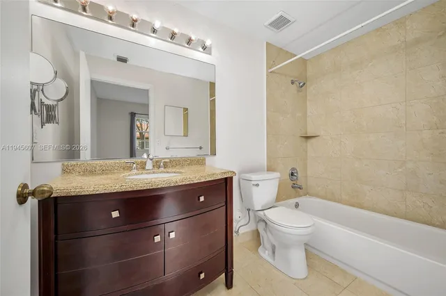 a bathroom with a granite countertop sink a toilet a mirror and shower