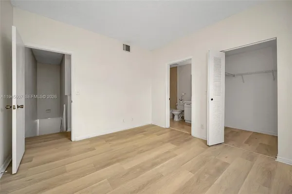 a view of an empty room with wooden floor and closet