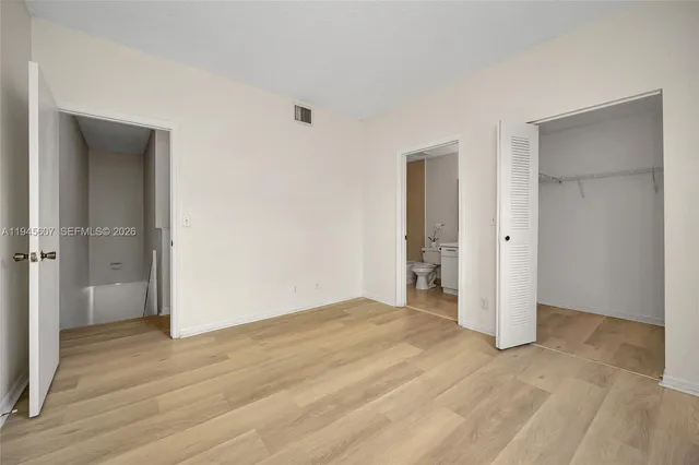 a view of an empty room with wooden floor and closet