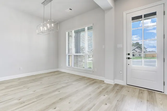 an empty room with wooden floor cabinet and windows