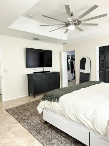 a spacious bedroom with a bed and a flat screen tv