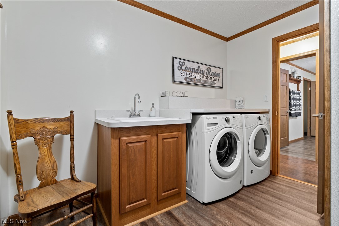 2240 Prysi Road Northwest Dover, OH 44622 - Photo 27 of 35 Laundry room with light wood-type flooring, sink, cabinets, and independent washer and dryer