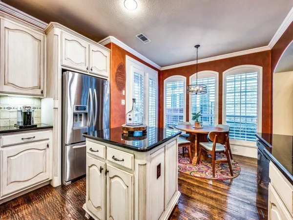 a kitchen with stainless steel appliances granite countertop a refrigerator a stove and white cabinets with wooden floor