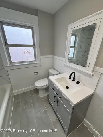 a bathroom with a sink a toilet and a window