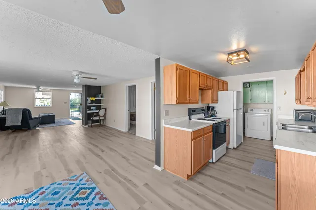 a kitchen with stainless steel appliances granite countertop a refrigerator a stove top oven a sink dishwasher and wooden cabinets with wooden floor