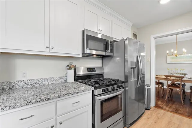 a kitchen with stainless steel appliances granite countertop a stove a refrigerator and a white cabinets