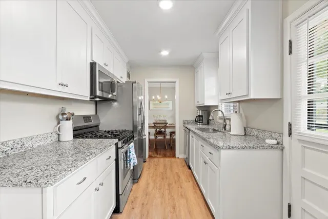 a kitchen with granite countertop kitchen island stainless steel appliances a sink stove and cabinets