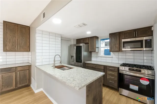 a kitchen with stainless steel appliances granite countertop a sink stove and refrigerator