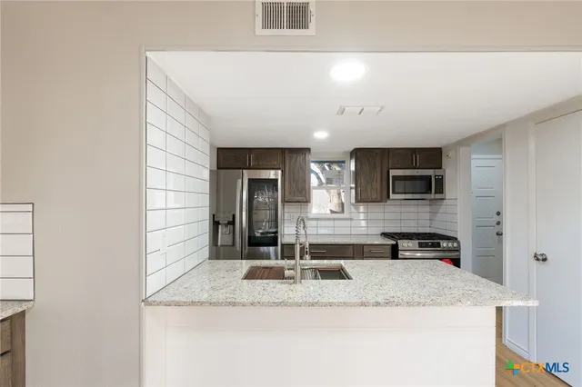 a spacious bathroom with stainless steel appliances granite countertop a sink and wooden floor