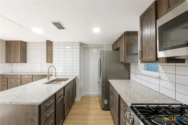 a kitchen with stainless steel appliances granite countertop a sink stove and refrigerator