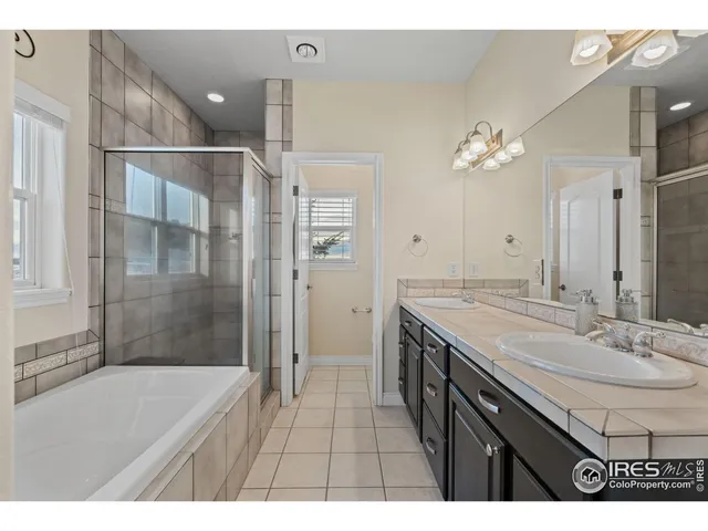 a bathroom with a sink double vanity granite tub shower and a mirror