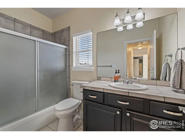 a bathroom with a granite countertop sink toilet a mirror a vanity and shower