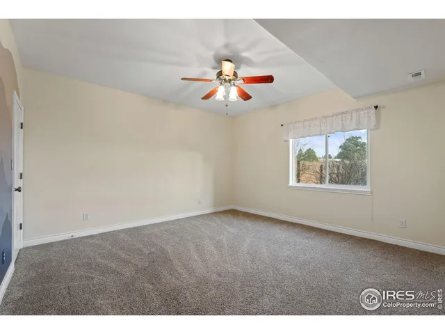 a view of an empty room with chandelier fan and window