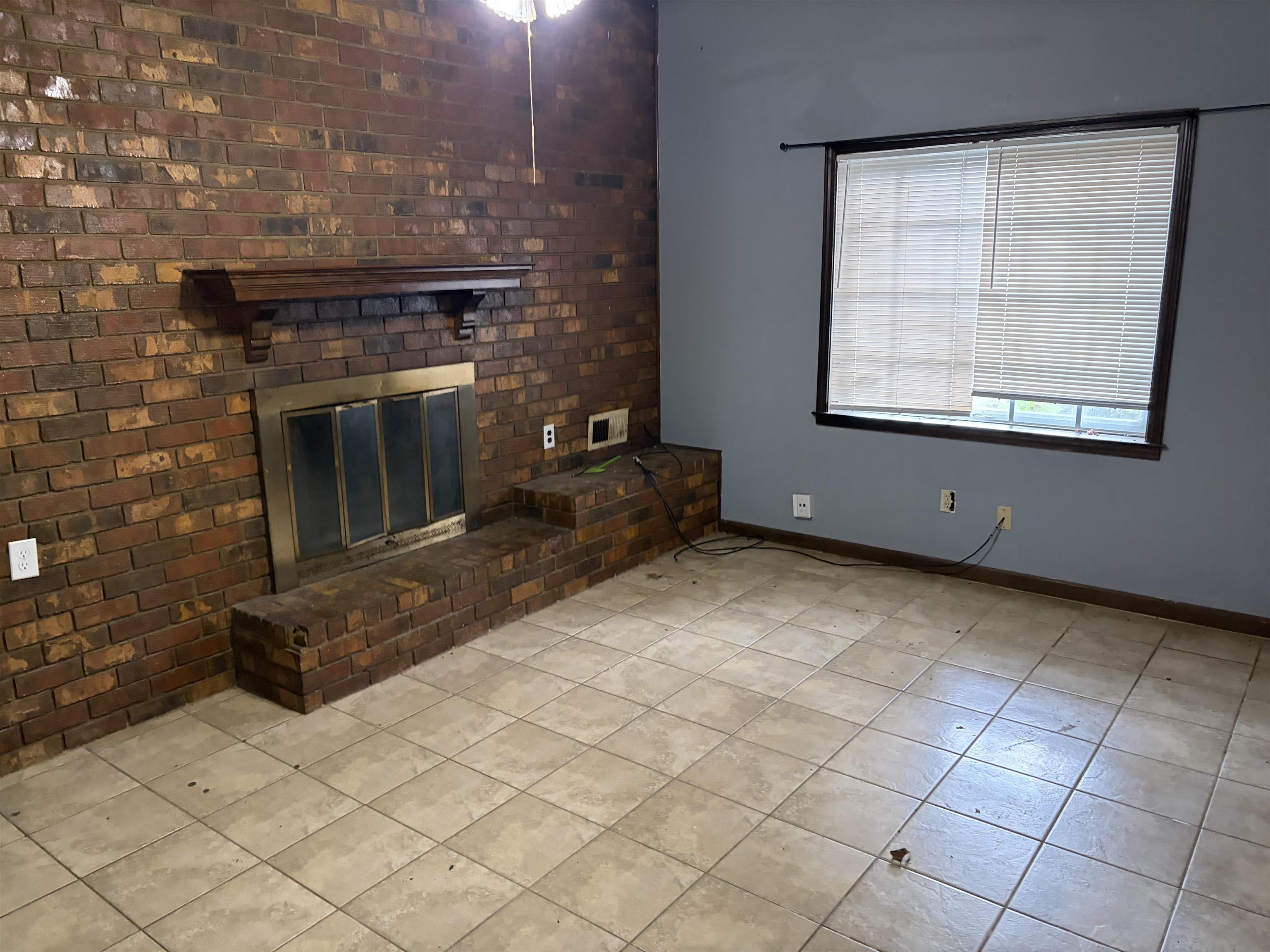 4993 Cedar View Road Memphis, TN 38118 - Photo 17 of 23 Brick fireplace with a wood mantle, integrated hearth, and tile flooring