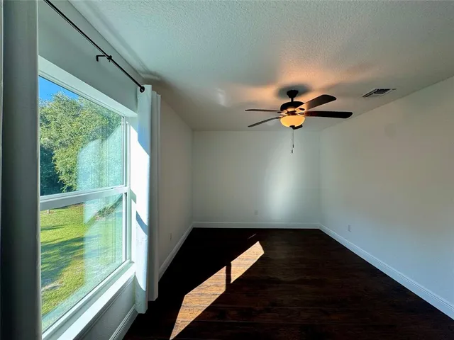 a view of empty room with wooden floor and fan