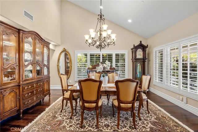 a kitchen with stainless steel appliances granite countertop a refrigerator a stove top oven a dining table and chairs with wooden floor