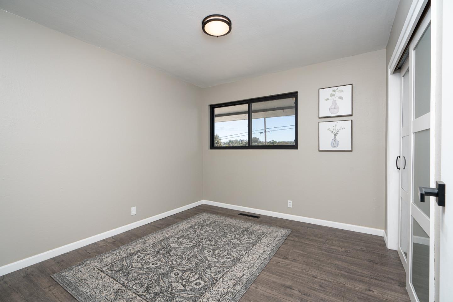 1055 Tweed Street Seaside, CA 93955 - Photo 15 of 33 an empty room with wooden floor and windows