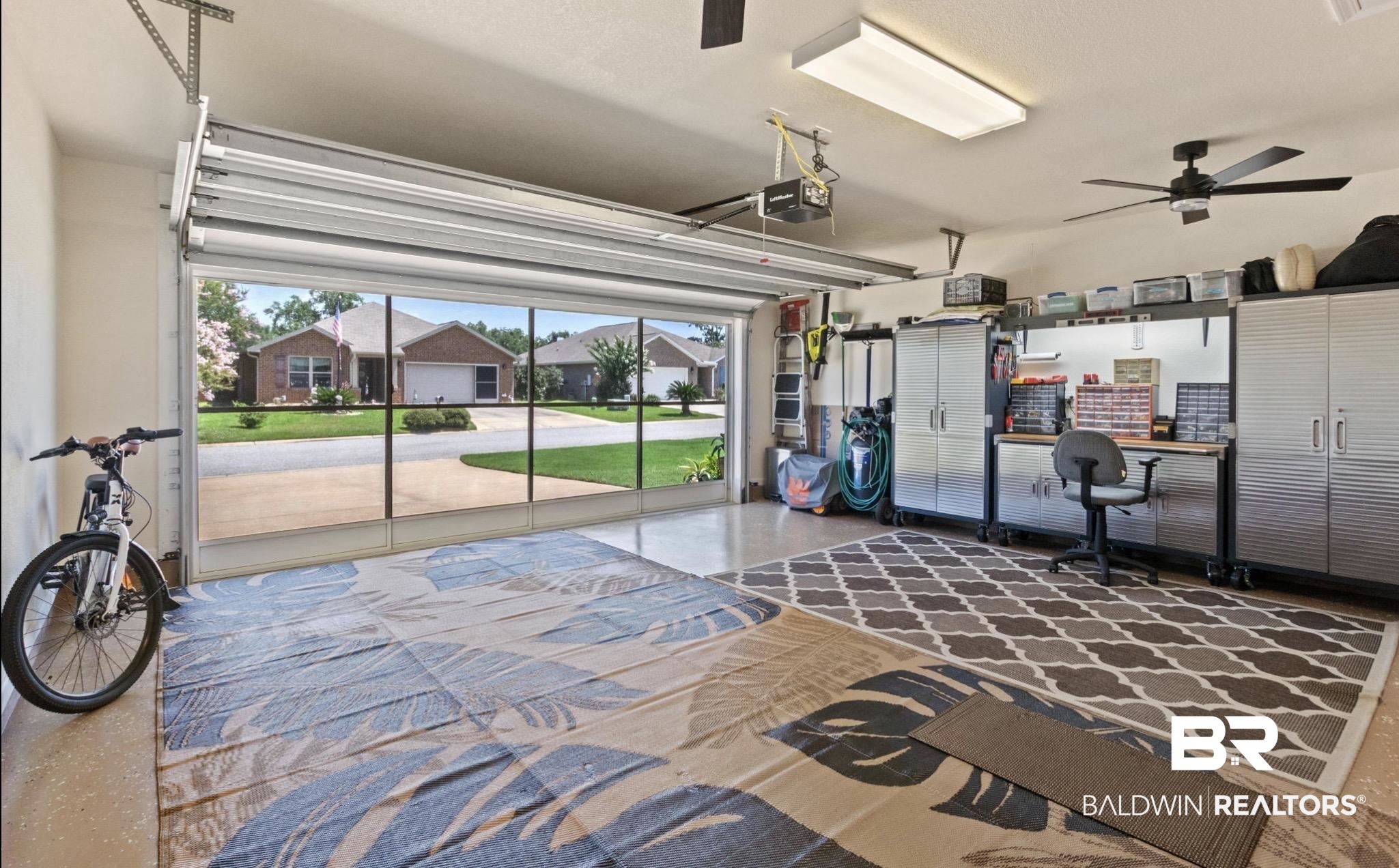 1676 Abbey Loop Foley, AL 36535 - Photo 21 of 31 Spacious garage featuring a glass-paneled overhead door, epoxy-coated flooring, built-in cabinetry, overhead lighting, and a ceiling fan