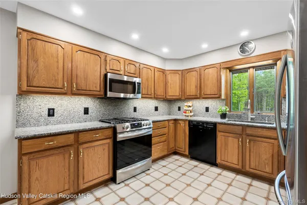 a kitchen with stainless steel appliances granite countertop a stove top oven a sink dishwasher a dining table and chairs with wooden cabinets