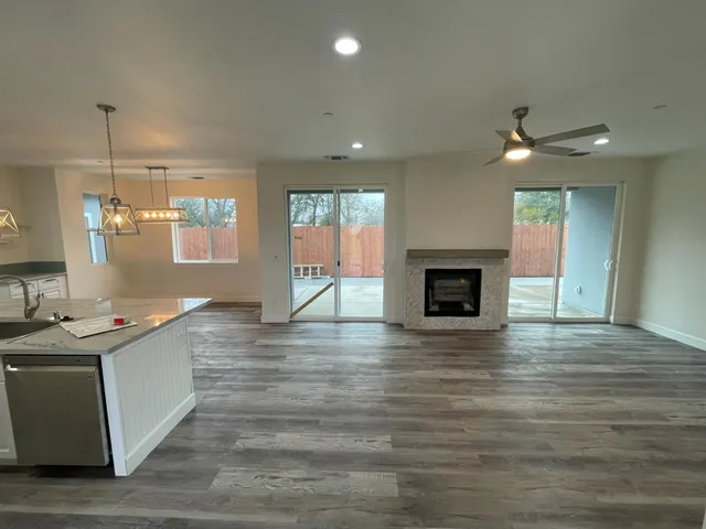 a view of a kitchen and a ceiling fan wooden floor and a fireplace