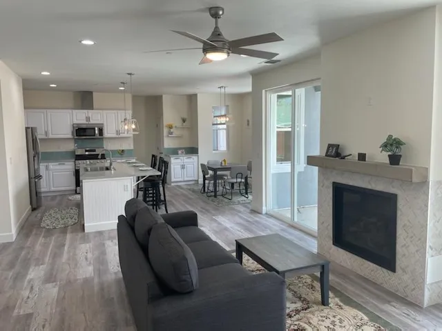 a living room with stainless steel appliances furniture a fireplace and a open kitchen view