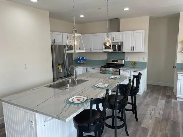 a kitchen with stainless steel appliances granite countertop a dining table chairs refrigerator and microwave