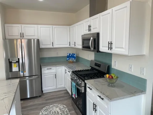 a kitchen with stainless steel appliances granite countertop a refrigerator stove top oven and sink