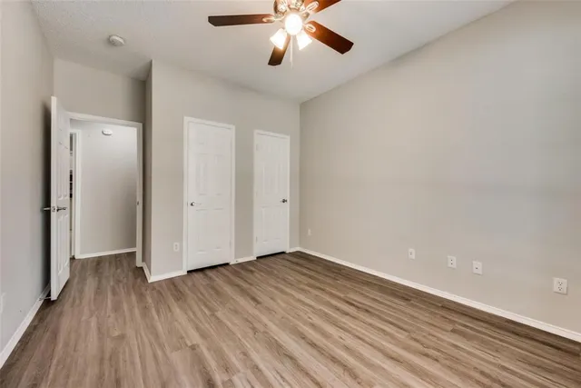 an empty room with wooden floor and a ceiling fan