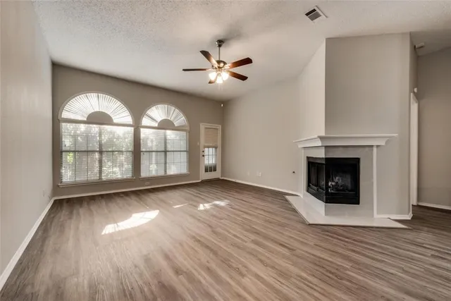 an empty room with wooden floor a fireplace a ceiling fan and wooden floor