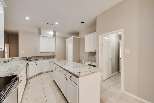 a large kitchen with a stove a sink a refrigerator and a granite counter tops