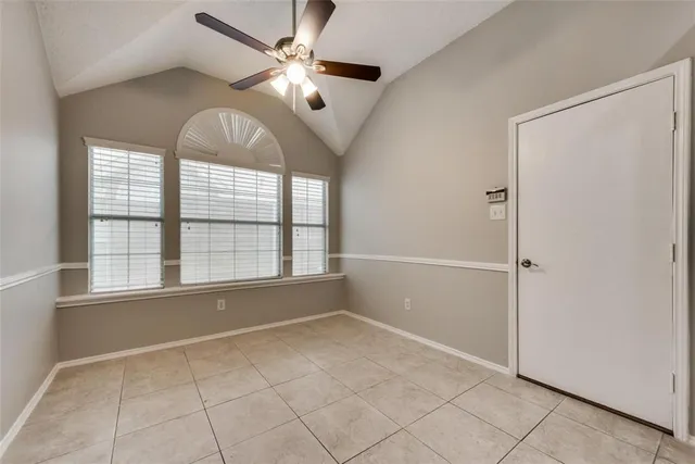 an empty room with chandelier fan and windows