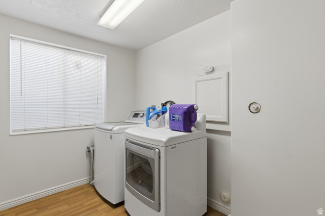 134 West 475 South Ogden, UT 84404 - Photo 22 of 27 Laundry area featuring washing machine and clothes dryer, light wood-style floors, and a textured ceiling