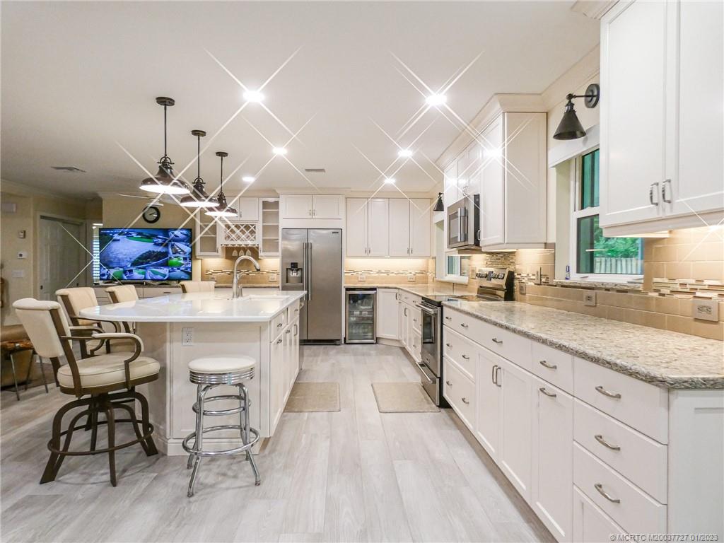 308 Southwest Ridge Lane Stuart, FL 34994 - Photo 13 of 43 a kitchen with stainless steel appliances kitchen island granite countertop a sink cabinets and wooden floor