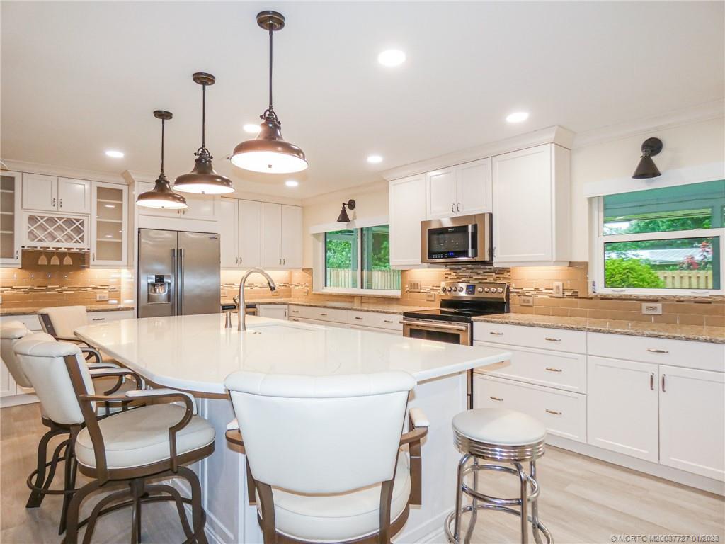 308 Southwest Ridge Lane Stuart, FL 34994 - Photo 14 of 43 a kitchen with stainless steel appliances a dining table chairs stove and sink