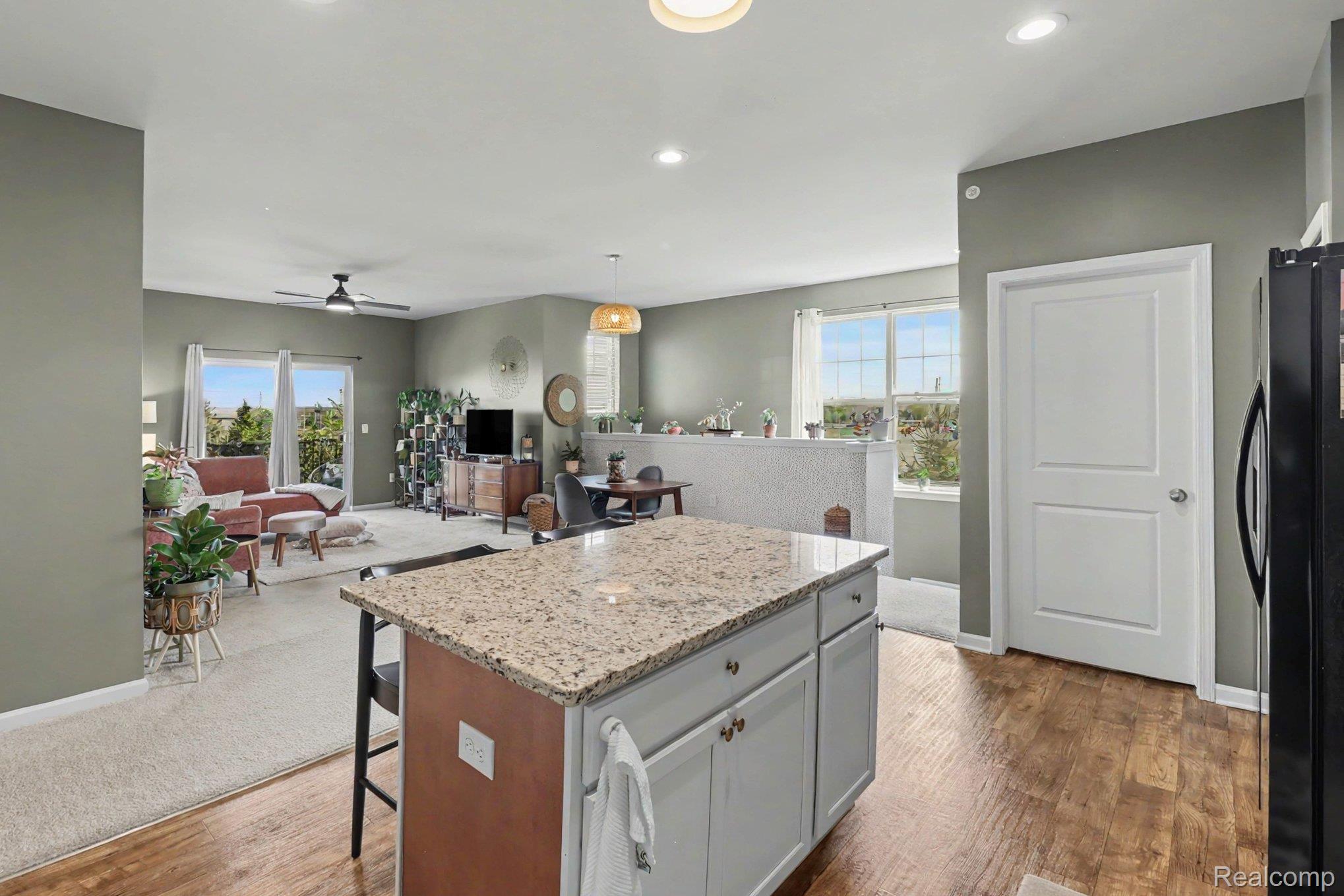 9864 Ridge Run Street Howell, MI 48855 - Photo 23 of 23 Kitchen featuring a kitchen island, a breakfast bar, open floor plan, light stone countertops, and freestanding refrigerator