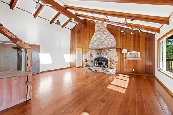 a view of empty room with wooden floor and fireplace