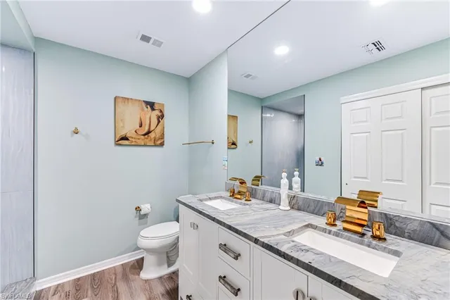 a bathroom with a granite countertop sink a toilet and a mirror