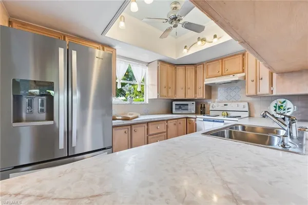 a kitchen with stainless steel appliances granite countertop a refrigerator a sink a stove a washer and dryer with wooden floor