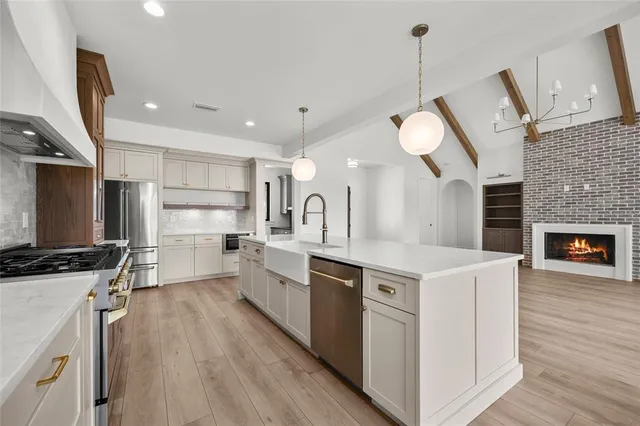 a large white kitchen with a large island oven a stove a dining table and chairs