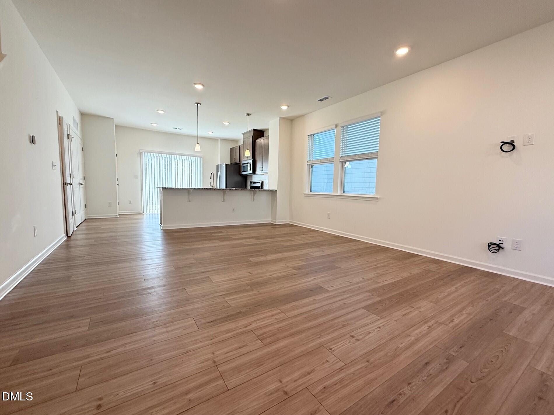332 Hacksaw Trail Raleigh, NC 27610 - Photo 5 of 29 an empty room with wooden floor and a kitchen