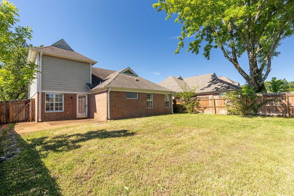 9768 Riggin Drive Memphis, TN 38002 - Photo 26 of 32 Spacious rear yard featuring an expansive grassy area, mature trees, and a wooden privacy fence