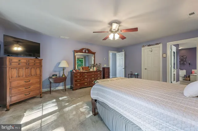 a spacious bedroom with a bed a dresser and a chandelier