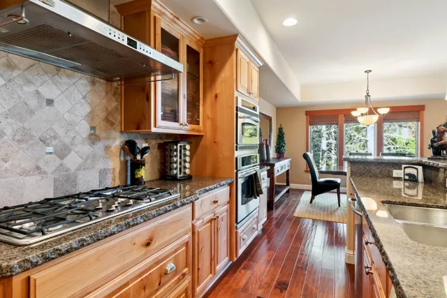 a kitchen with stainless steel appliances granite countertop a stove a refrigerator a oven a sink with a dining table and chairs