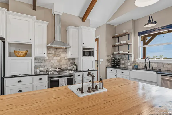 a kitchen with stainless steel appliances kitchen island granite countertop a stove a sink and white cabinets