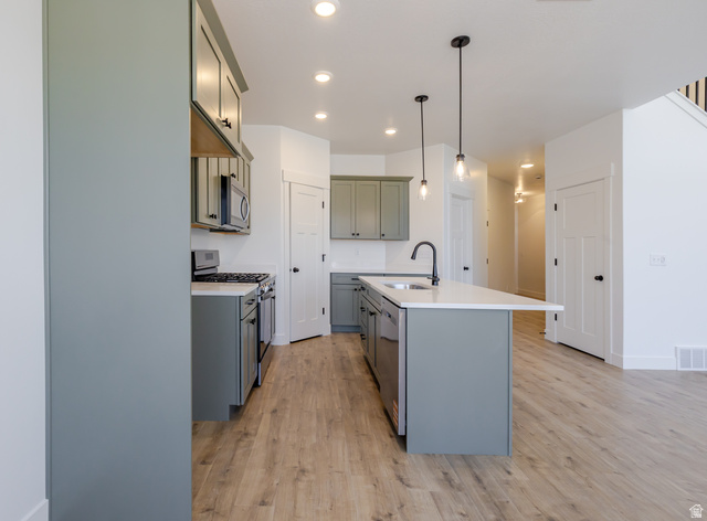 4752 Heartwood Road, Unit 433 Mapleton, UT 84664 - Photo 7 of 20 Kitchen with stainless steel appliances, light wood-style flooring, decorative light fixtures, a kitchen island with sink, and light stone counters