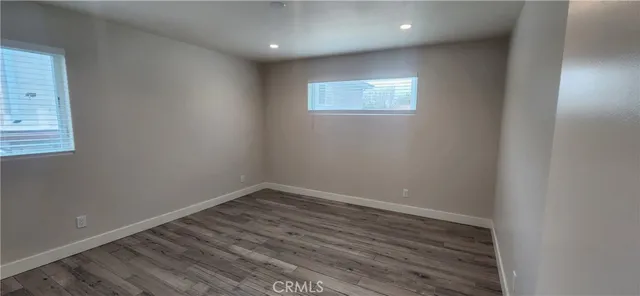 en empty room with wooden floor and windows