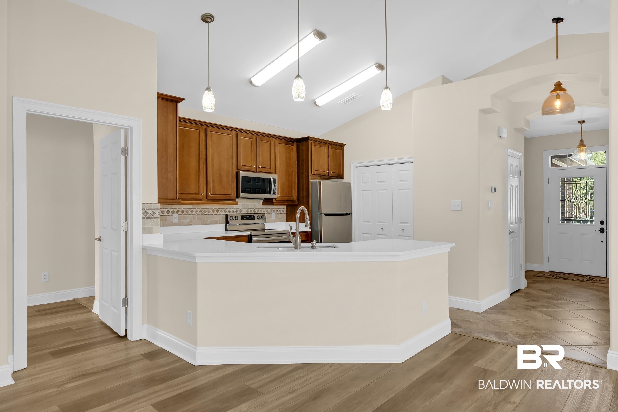 226 Hemingway Loop Foley, AL 36535 - Photo 15 of 53 Kitchen with decorative backsplash, brown cabinetry, pendant lighting, light wood-type flooring, and appliances with stainless steel finishes