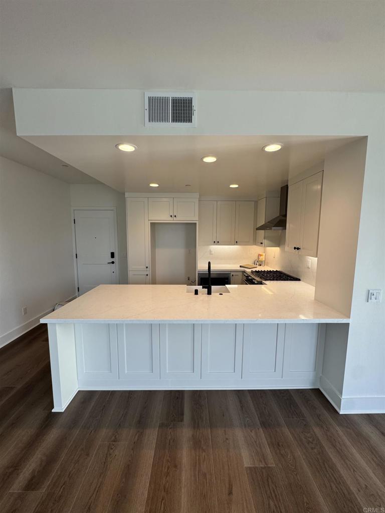 1105 Catania Court, Unit 201 Encinitas, CA 92024 - Photo 5 of 19 a large white kitchen with kitchen island sink stainless steel appliances and cabinets